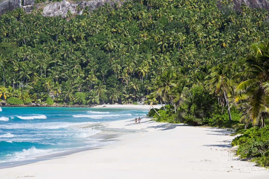 Couple walking on the beach at North Island Seychlles