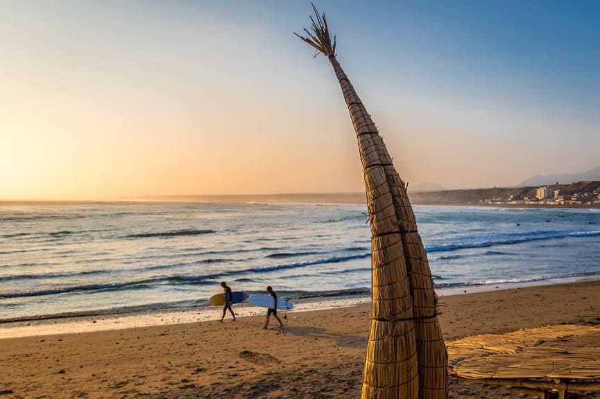 Two surfers walking along Tuquillo Beach in Peru