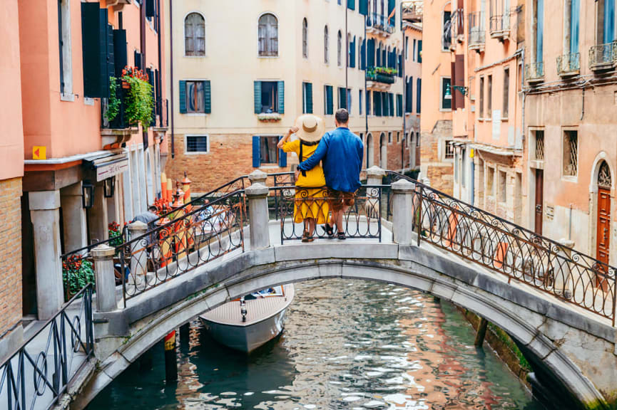 Couple sitting an a canal bridge in Venice, Italy