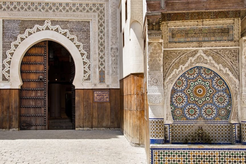 Rich decoration on the entrance to Funduq al-Najjariyyin with neighboring fountain in Fes