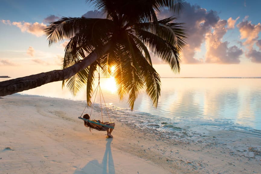 Woman lounging in a hanging chair watching the sunset in the Maldives