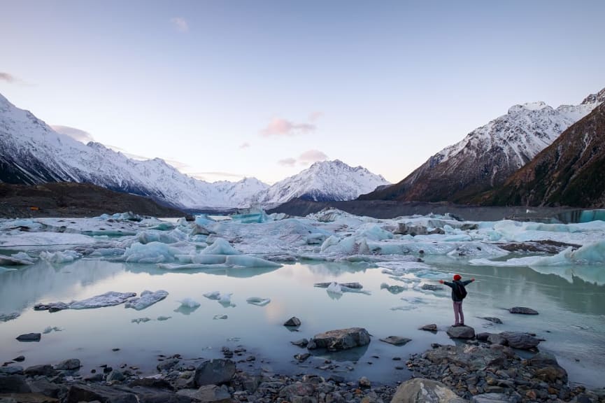 Traveler viewing the amazing icebergs and snow mountains during dusk in Mount Cook National Park, New Zealand.