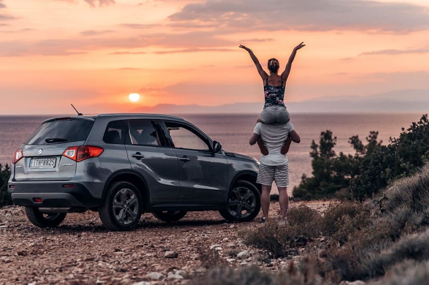 Couple with parked car enjoying the sunset in Greece.