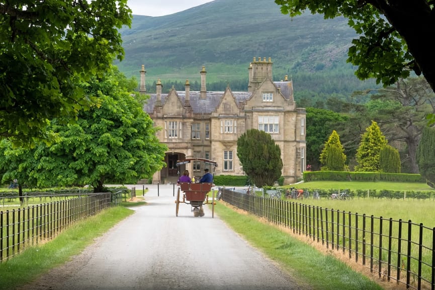 Couple having a carriage ride and Muckross House in Killarney National Park, Ireland