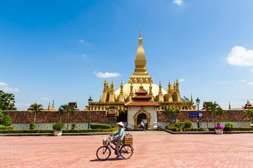 Man riding bicycle in front of Pha That Luang pagoda in Vientiane, Laos