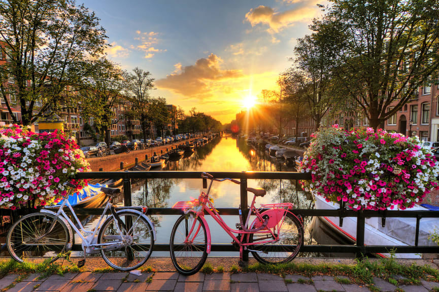 Bikes parked on a canal bridge during sunrise in Amsterdam, the Netherlands