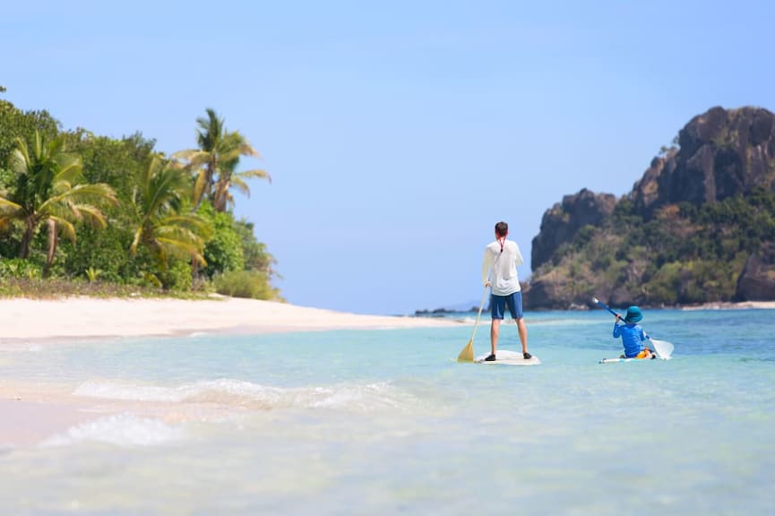 Father and son stand-up paddle boarding, Fiji