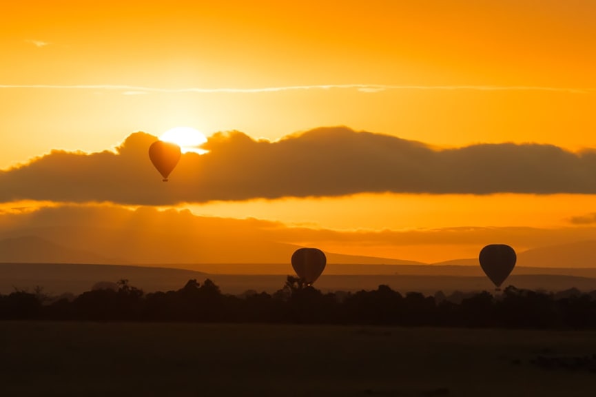 Hot air balloons drifting over the Maasai Mara savannah at dawn 