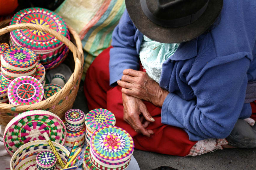 Woman selling handmade wicker boxes at a Andean market in Ecuador