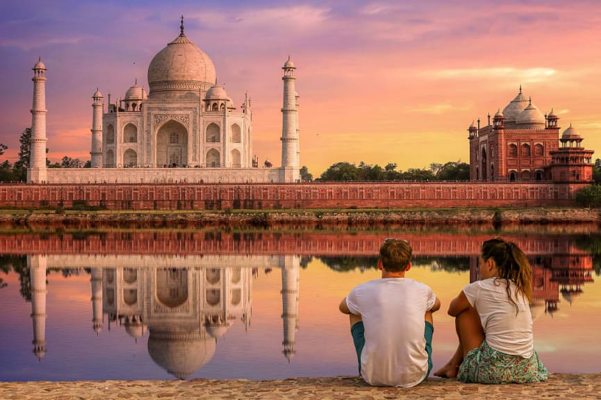 Couple watching the sunset behind the Taj Maja from the banks of the Yamuna River in Agra, India