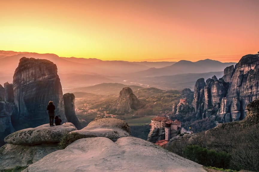 Couple enjoying the breathtaking view of Meteora with the Roussanou Monastery at sunset