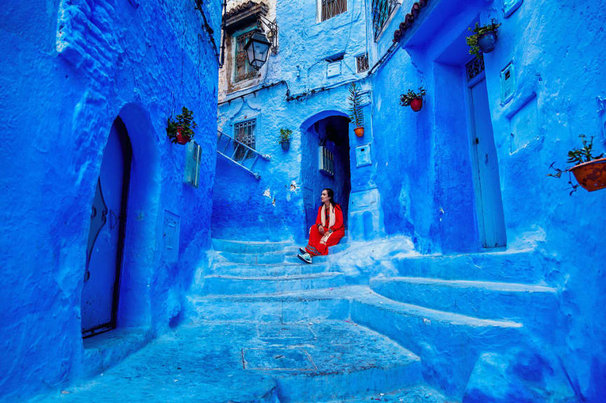 Woman sitting on stairs in Chefchauen, the Blue City of Morocoo.