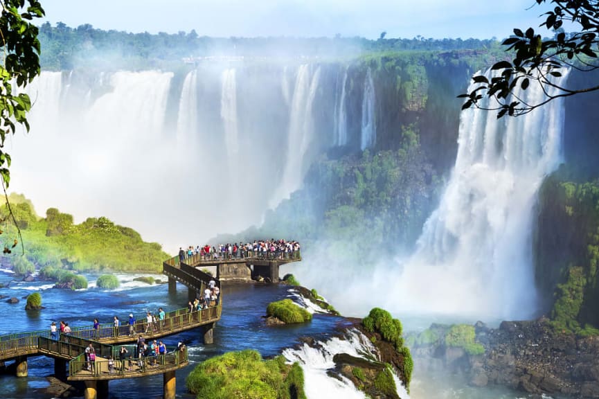 Tourist on bridge walkway and viewing platform taking in the massive waterfalls at Iguazu in Argentina