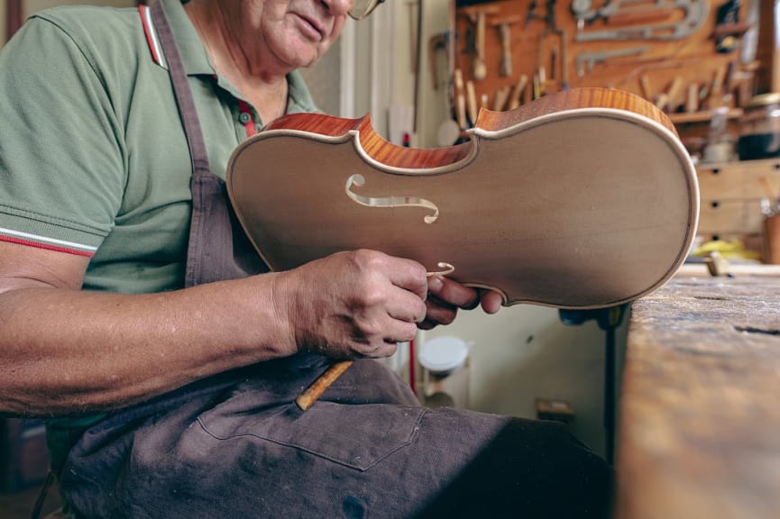 Luthier, violin maker, carving and sculpting the f holes of a violin in Cremona, Italy