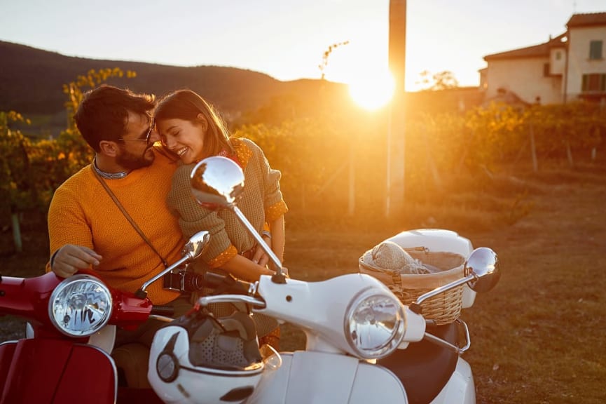 A young couple shares an embrace at a vineyard in Italy.