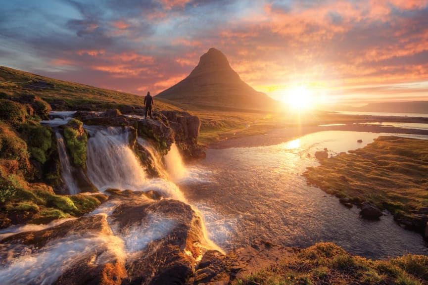 Silhouette of man watching the sunset over Kirkjufellsfoss with Kirkjufell mountain in Iceland