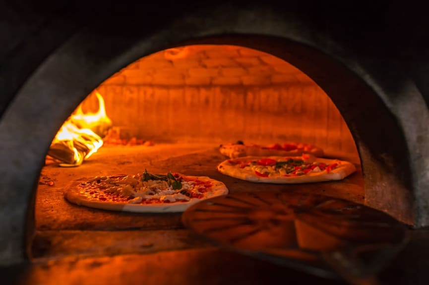 Three pizzas in a brick oven