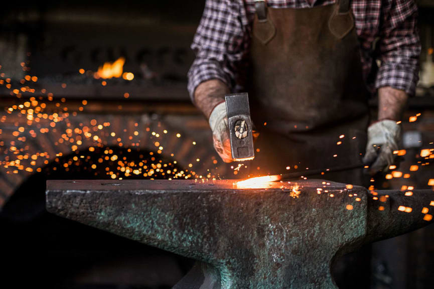 Close-up of blacksmith working with hammer at anvil in his workshop