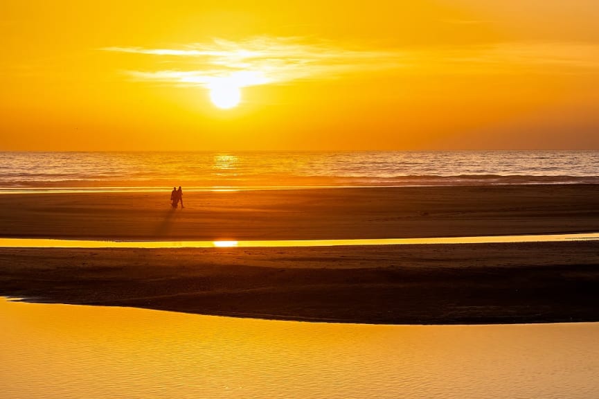 Couple walking on the beach at sunset in Cadiz, Spain