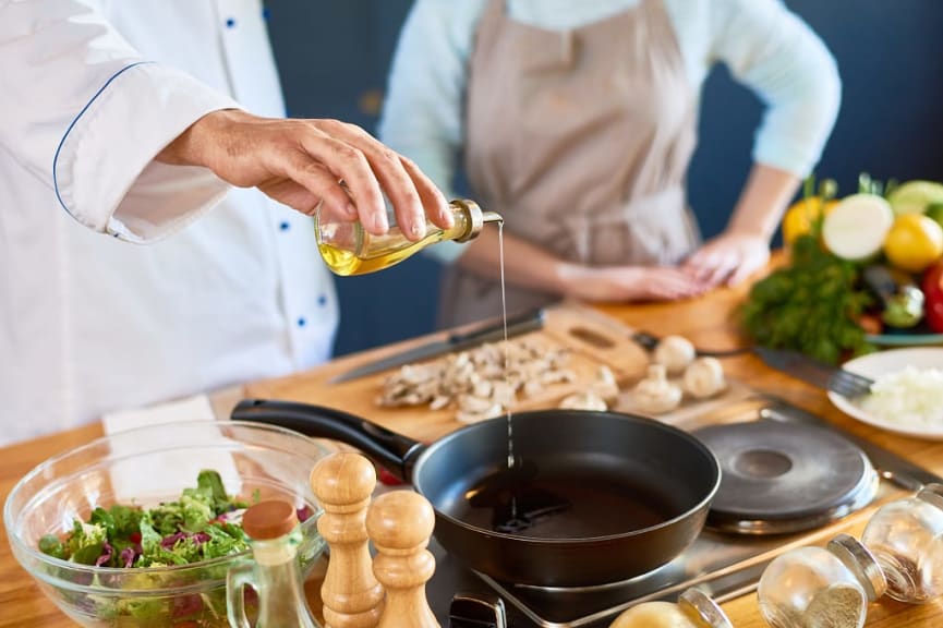 Chef instructor pouring oil into a pan 