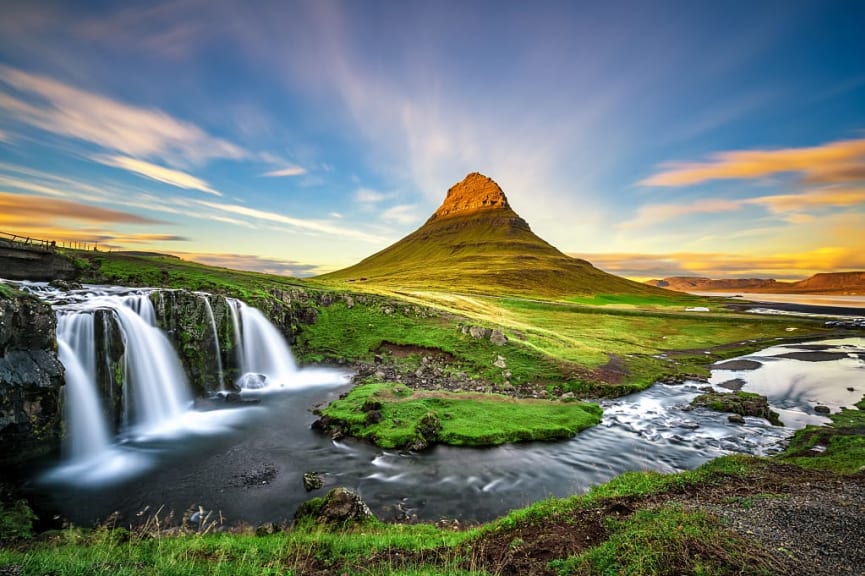 Sunset over the Kirkjufellsfoss waterfall with Kirkjufell mountain in the background in Iceland