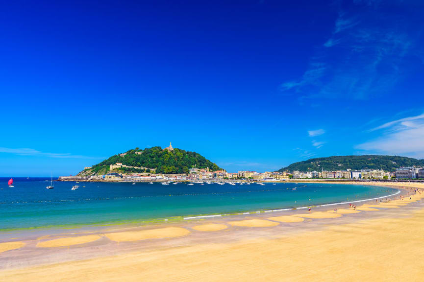 Golden sand against azure waters and blue sky on a sunny day at La Concha Beach in San Sebastian, Spain