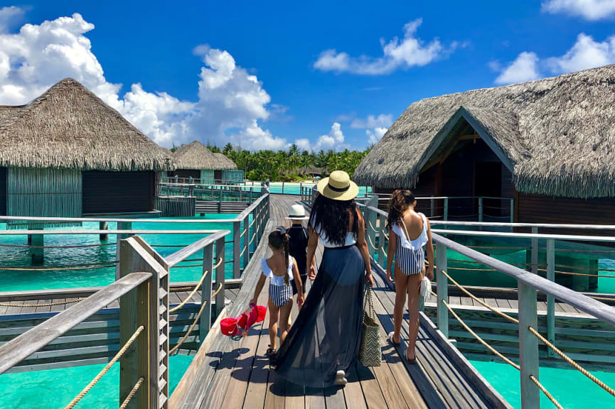 Family walking on jetty towards overwater bungalows in Bora Bora, French Polynesia