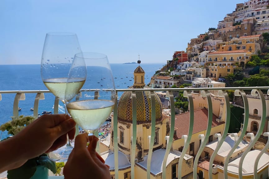 Couple holding wine glasses with Positano view on the Amalfi Coast
