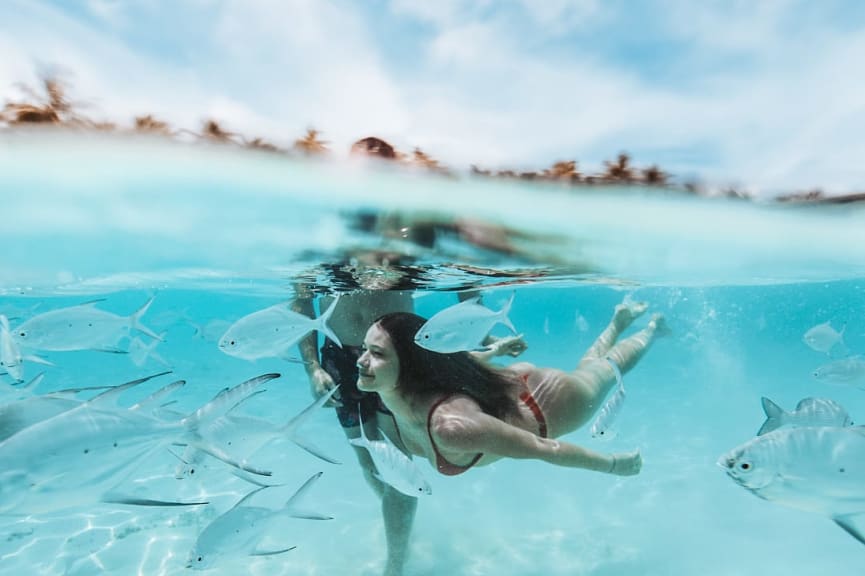 A couple swims in the ocean in the Maldives.