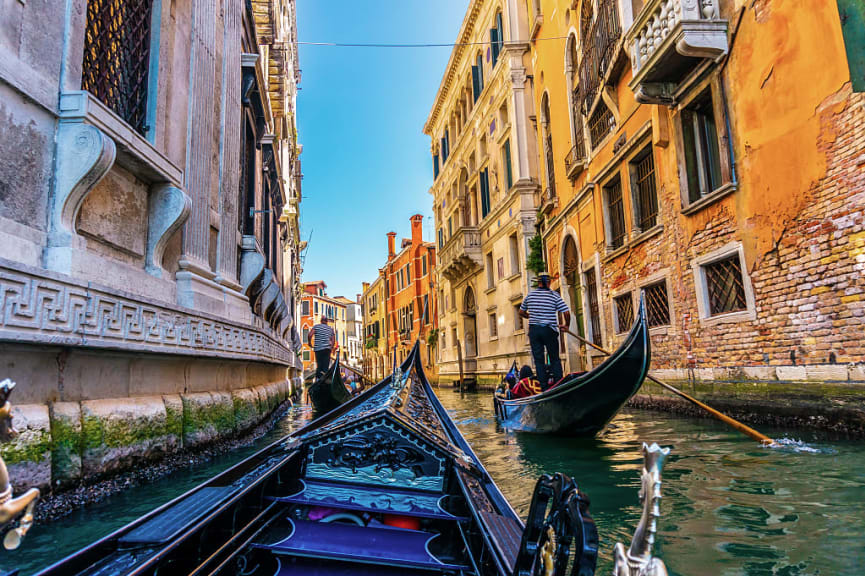 Gondoliers in sun filled canal in Venice, Italy,