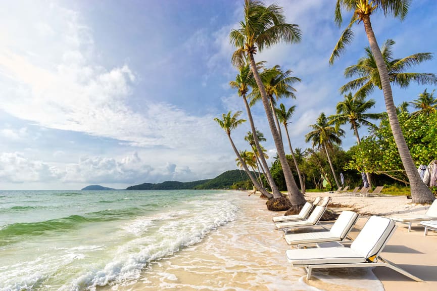 Sunbeds under tropical palms at Bai Sao beach in Vietnam.