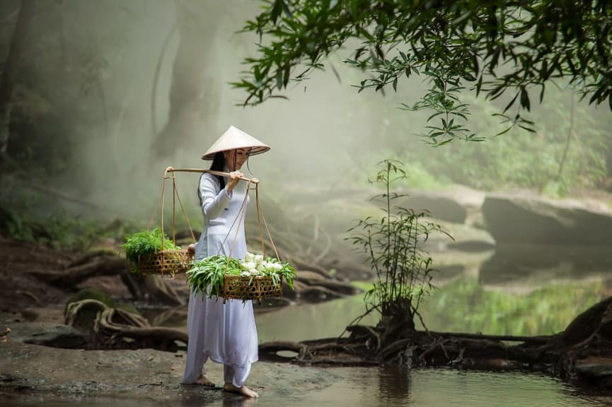 Woman wearing a traditional Vietnamese dress and hat in the forest in Vietnam