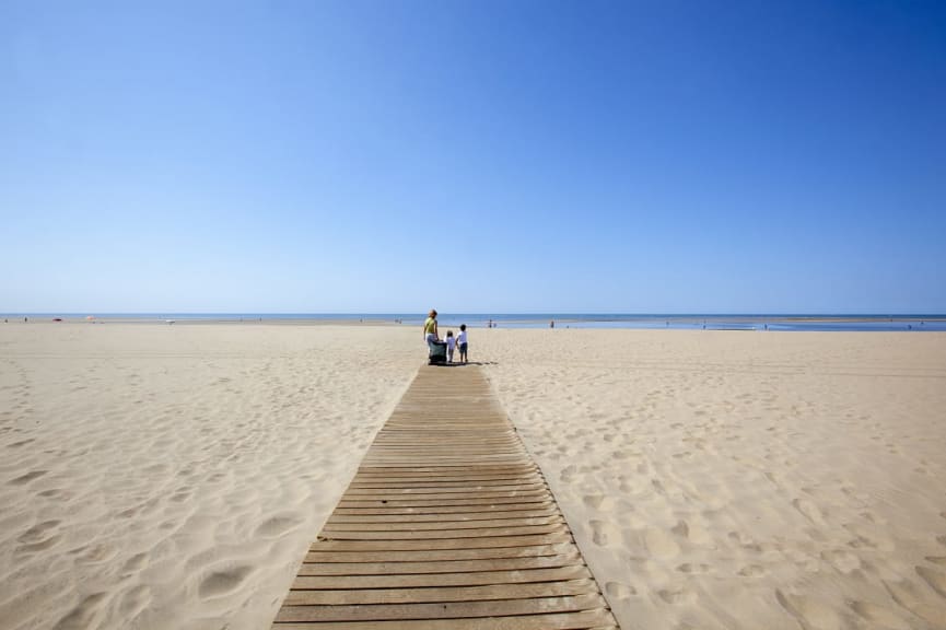 Family a the end of a walkway on the beach in Isla Canela, Spain