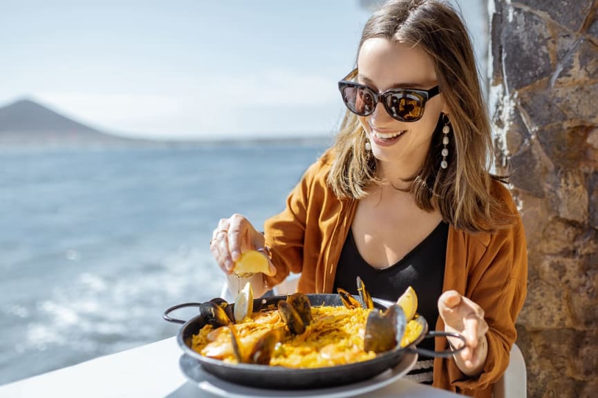 Woman eating paella while sitting at the restaurant terrace in coastal Spain