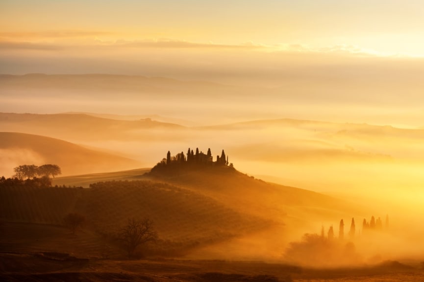 Sunrise with rays over the foggy valleys in Val d'Orcia, Tuscany