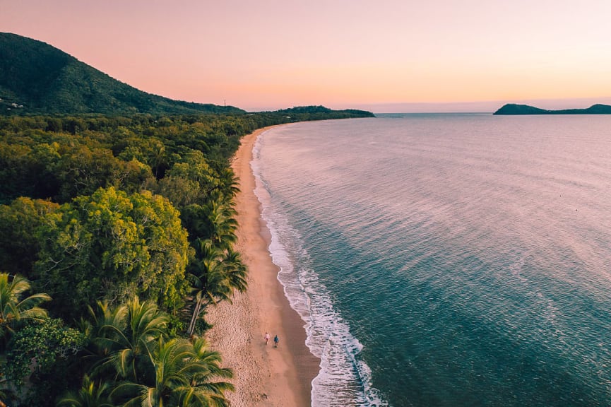 Couple enjoying a sunset walk on the long stretch of Clifton Beach in Palm Cove, Queensland