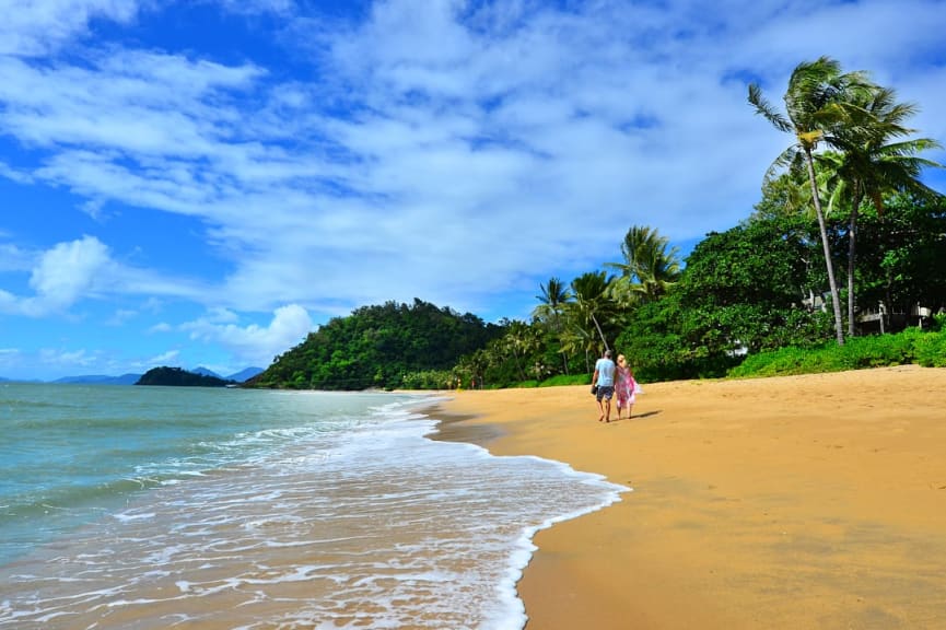 Couple walking along Trinity Beach in Cairns, Australia.