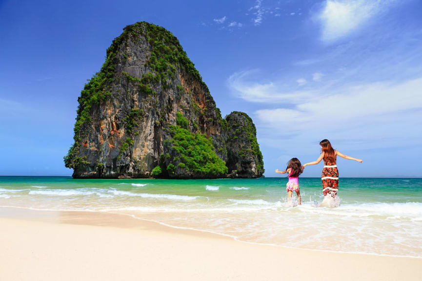 Mother and daughter running in the water on Railay beach in Krabi, Thailand