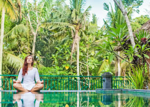 Woman meditating poolside at luxury resort in Bali