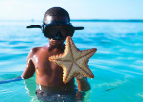 Young boy shows off a starfish he found while snorkeling in Belize