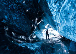 Mountain climber standing inside ice cave glacier