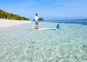 Father and son stand up paddle boarding in Fiji