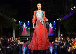 Runway model in a red dress at a fashion show. Credit: Ahmad Ardity