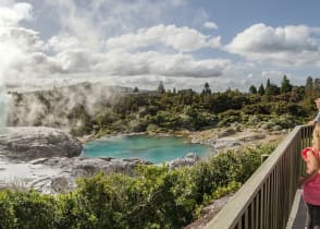 Family viewing the geothermal lake and geyser at Te Puia in Rotorua, New Zealand