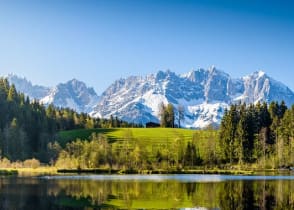 Idyllic alpine scenery, snowy mountains mirroring in a small lake in Tyrol, Austria.