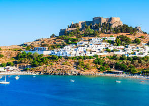 Lindos acropolis on hill above white houses and blue ocean bay in Rhodes, Greece