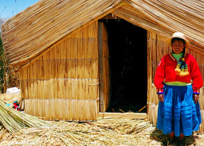 A girl standing on a floating Uros island standing in front of her home in Lake Titicaca, Peru.