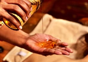 Women getting ayurvedic massage with oil in India.