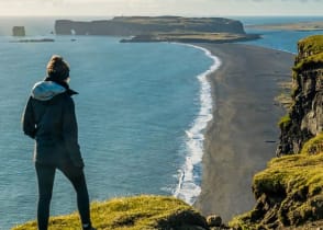 Hiker enjoying view of Reynisfjara black sand beach and Dyrholaey in the distance