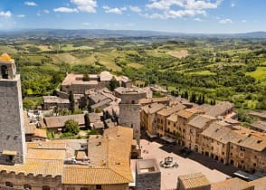 San Gimignano surrounded by the green rolling hills and vineyards of Tuscany, Italy